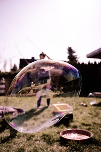 Close-up of crystal ball on glass against sky