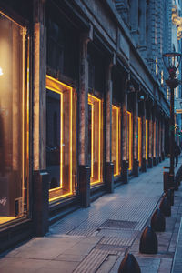 Illuminated street amidst buildings at night