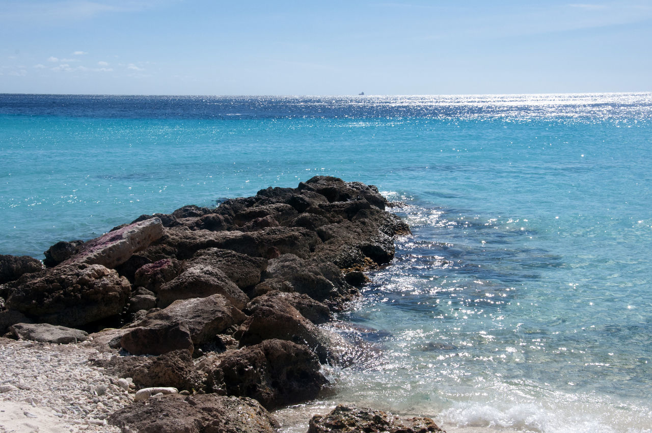 sea, water, land, body of water, beach, ocean, beauty in nature, shore, sky, scenics - nature, rock, wave, nature, horizon, horizon over water, wind wave, coast, blue, motion, tranquility, no people, tranquil scene, day, idyllic, outdoors, travel destinations, vacation, sand, cliff, islet, coastline, bay, non-urban scene, terrain, travel, sports, sunlight, cove, cloud, water sports, rock formation