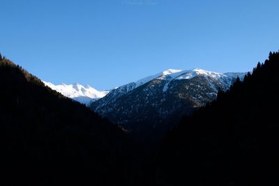 Scenic view of snowcapped mountains against clear blue sky