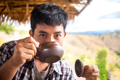 Portrait of young man drinking tea in hut