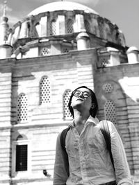 Portrait of young woman standing against building