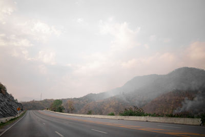 Empty road along mountain range against sky