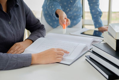 Close-up of people using laptop on table