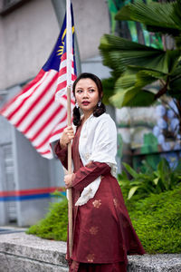 Portrait of young woman standing against trees