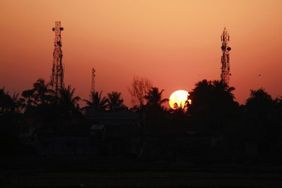 Silhouette trees and buildings against sky during sunset