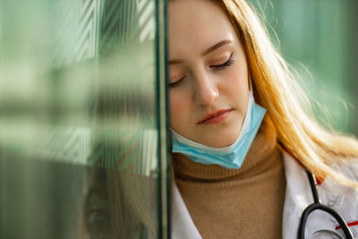 Tired doctor leaning on glass wall