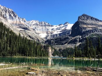 Scenic view of lake and mountains against clear blue sky