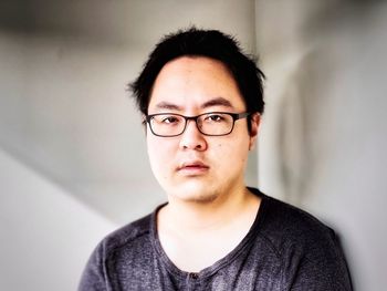 Portrait of young man wearing eyeglasses against wall