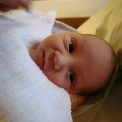 Close-up of baby boy relaxing on bed at home