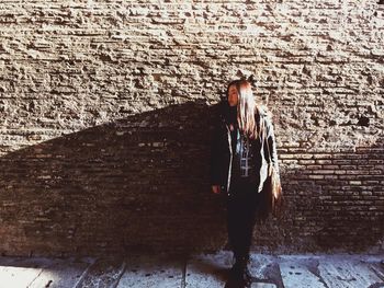 Rear view of woman standing against brick wall