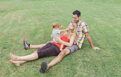 High angle view of happy family sitting on field