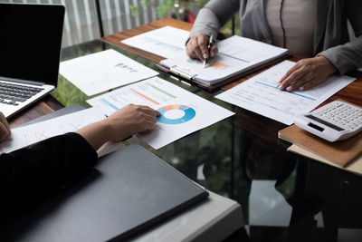 Midsection of business colleagues working on table