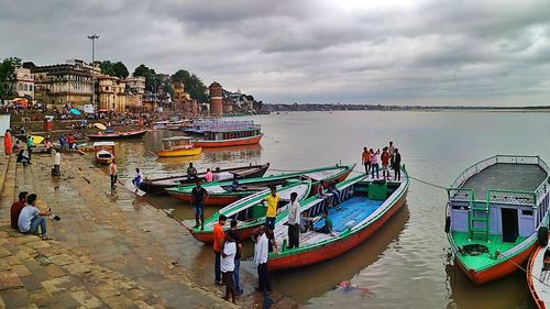 People on boats moored in sea against sky