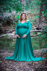 Portrait of young pregnant woman standing in forest