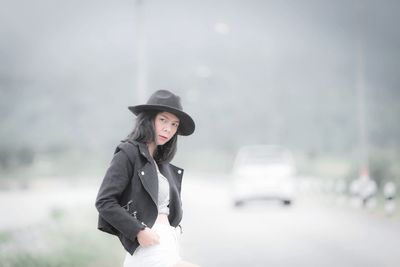 Portrait of mid adult woman wearing hat and leather jacket standing on road