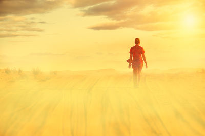 Full length of woman walking on sand in desert against sky