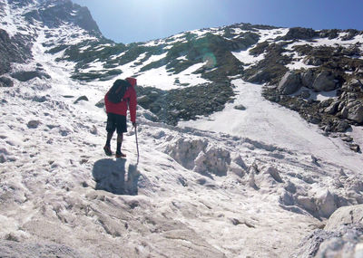 Rear view of hiker walking on snowcapped mountain