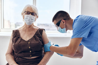 Nurse wearing mask vaccinating patient at clinic