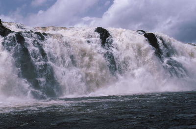 Scenic view of waterfall against sky