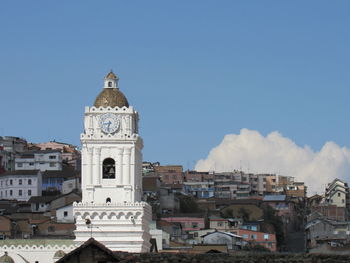 Clock tower amidst buildings in city against sky