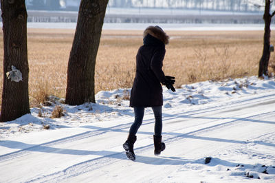 Rear view of woman standing on snow covered land