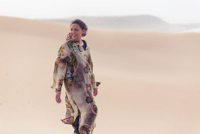 Full length of woman standing on desert against sky