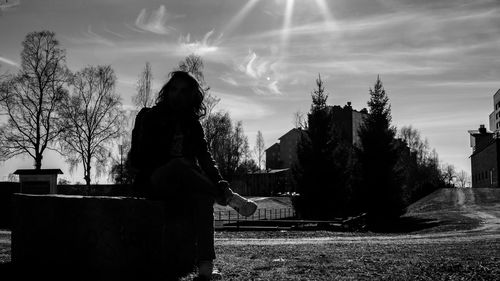 Woman by trees against sky