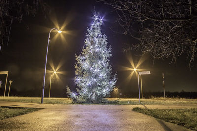 Illuminated street light on road at night