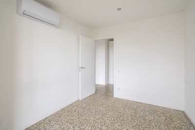 Interior of empty apartment, white room with air conditioning and tiled floor