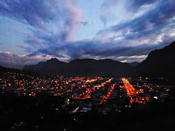 Illuminated cityscape against sky during sunset