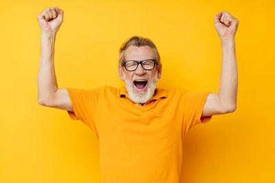 Portrait of happy senior man against yellow background