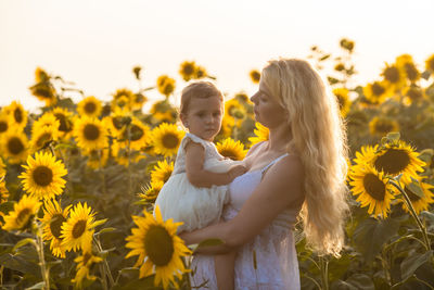 Mother with daughter standing in sunfower field