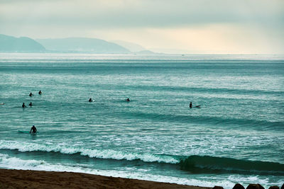 Scenic view of sea with silhouette people against sky in the morning