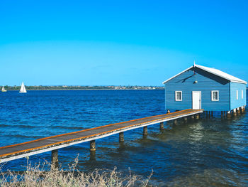 Building by sea against clear blue sky