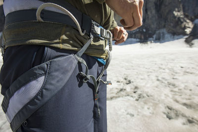 Mountain climber tightens his climbing harness prior to climbing.