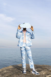 Rear view of woman standing on beach against sky