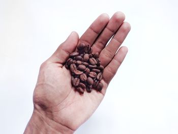 Close-up of hand holding coffee cup against white background