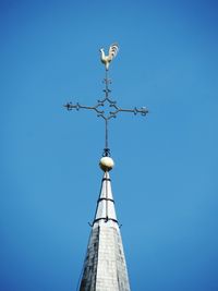 Low angle view of weather vane against blue sky