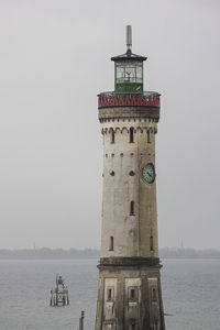 View of lighthouse by sea against clear sky