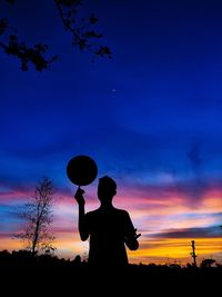 Silhouette man standing on field against sky during sunset