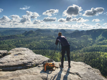 Rear view of man and dog on mountain against sky