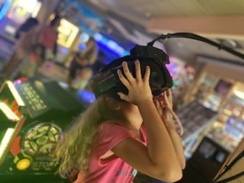 A girl is playing virtual games holding a camera on her head by hands