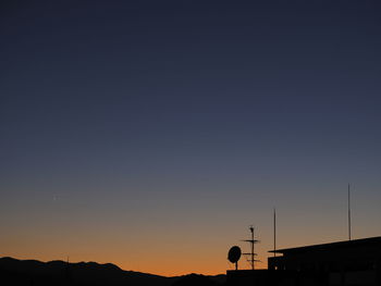 Low angle view of silhouette telephone against clear sky during sunset