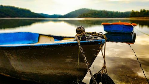 Fishing boat moored in lake against sky