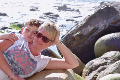 Portrait of smiling mother with son on rock