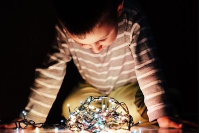 Boy looking illuminated string lights at home