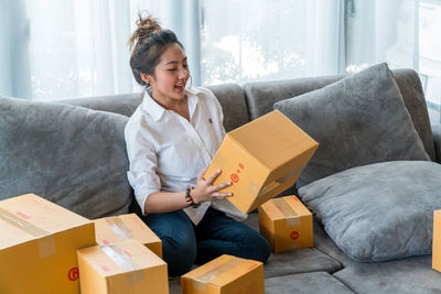 Young woman sitting on sofa in box