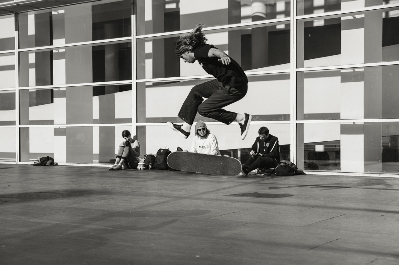 PEOPLE SKATEBOARDING IN FRONT OF MAN