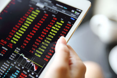 Cropped image of businesswoman analyzing stock market data on digital tablet in cafe